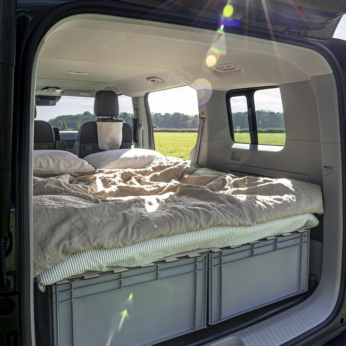 Gemütliches Camper-Bett im KIA PV5: Matratze auf KIUBIQ Eurobox-Deckeln bildet eine ebene Schlafgelegenheit im Minicamper