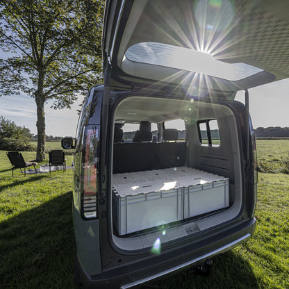 Modularer Kofferraum-Ausbau für KIA PV5: KIUBIQ Eurobox-Bett-System mit hellen Puzzle-Holzdeckeln in der Natur bei Sonnenschein