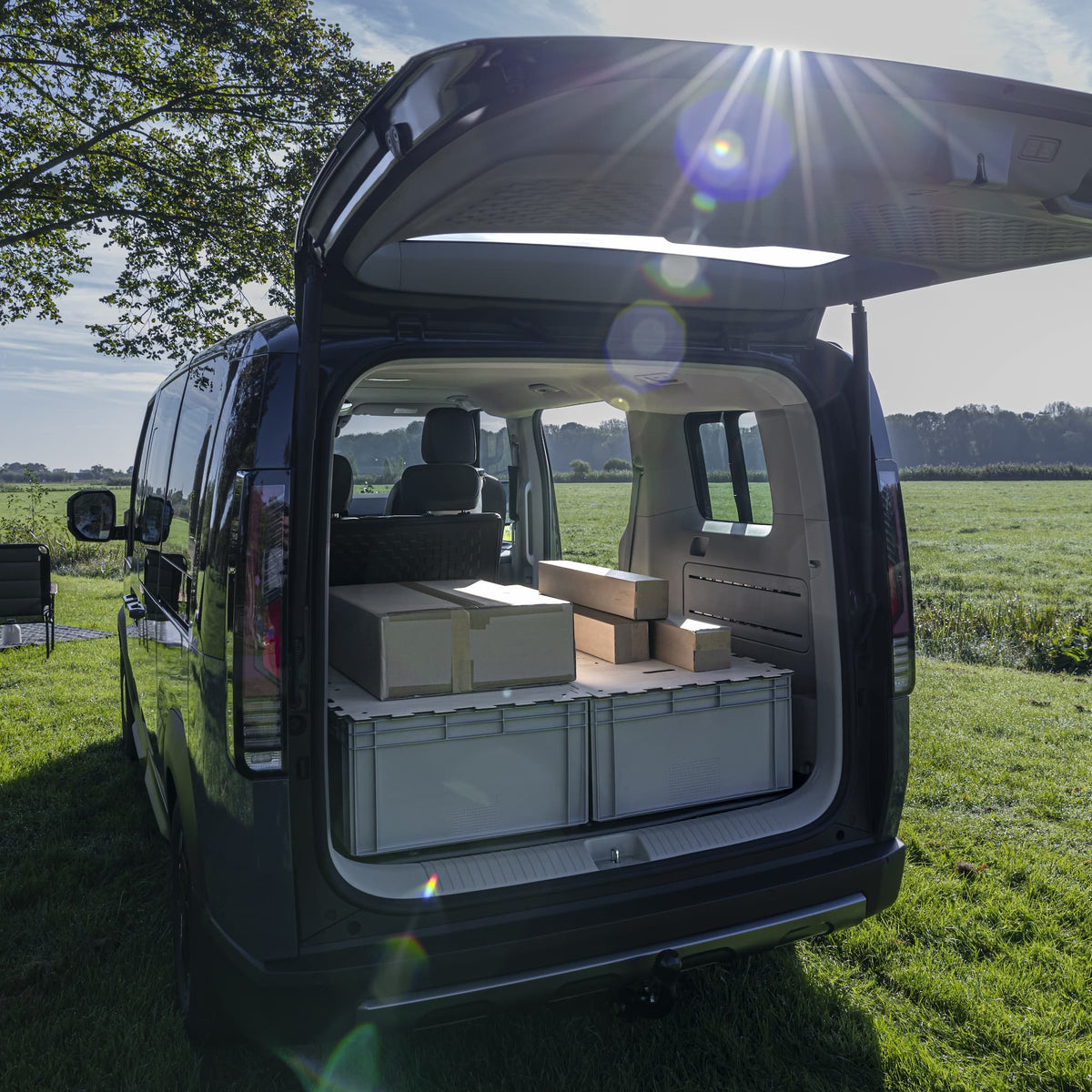Modularer Kofferraum-Ausbau für KIA PV5: KIUBIQ Eurobox-Transport-System mit hellen Puzzle-Holzdeckeln in der Natur mit umgeklappter Rücksitzbank und ebener Ladefläche