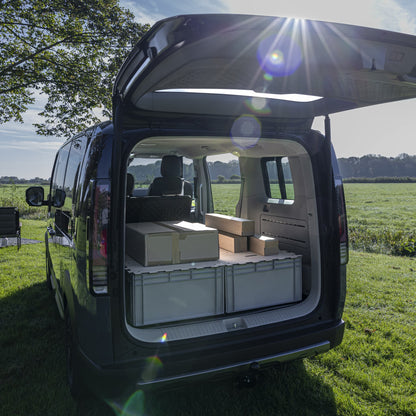 Modularer Kofferraum-Ausbau für KIA PV5: KIUBIQ Eurobox-Transport-System mit hellen Puzzle-Holzdeckeln in der Natur mit umgeklappter Rücksitzbank und ebener Ladefläche