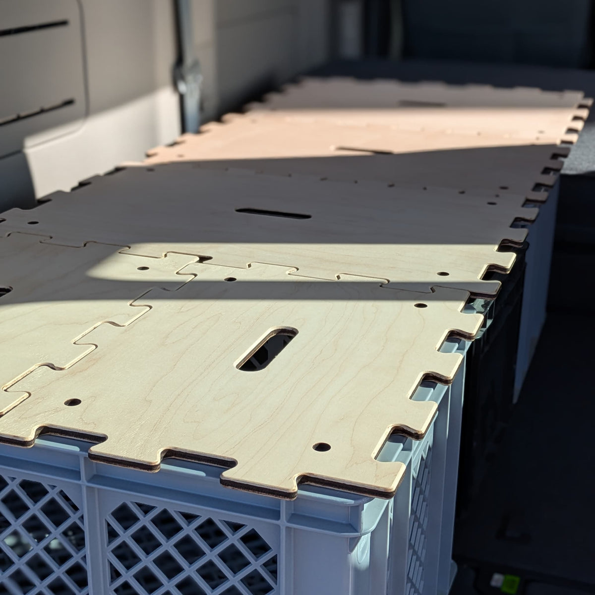 Detailaufnahme: Ahorn-Puzzledeckel bilden ein schmales Bett im Heck des KIA PV5 Passenger