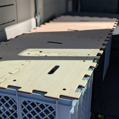 Detailaufnahme: Ahorn-Puzzledeckel bilden ein schmales Bett im Heck des KIA PV5 Passenger